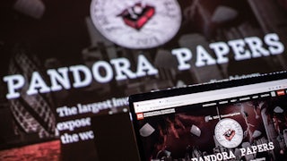A photograph illustration shows the logo of Pandora Papers in the background, in front of a laptop computer.