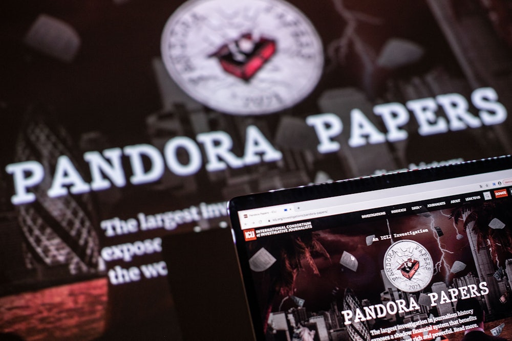 A photograph illustration shows the logo of Pandora Papers in the background, in front of a laptop computer.