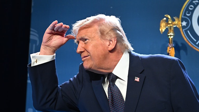 Donald Trump holds his hand above his eyes and turns and looks to his right