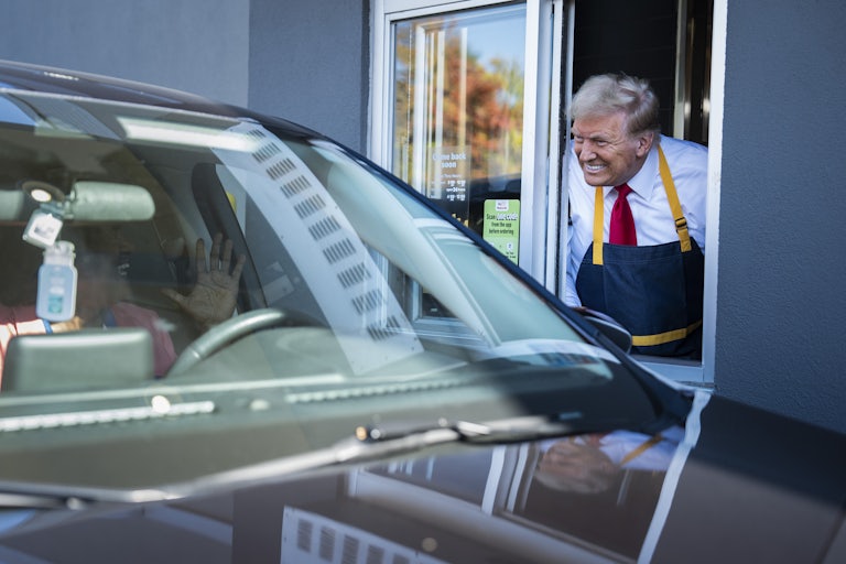 Donald Trump smiles while leaning out of a drive-through window