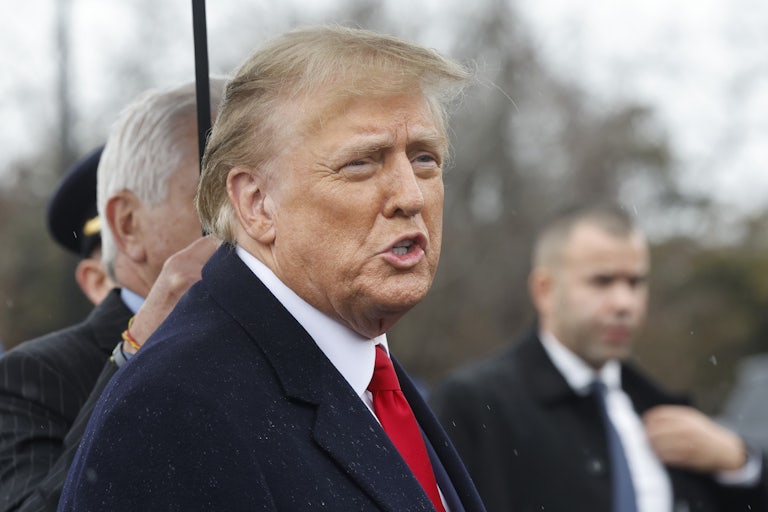 Donald Trump stands under an umbrella