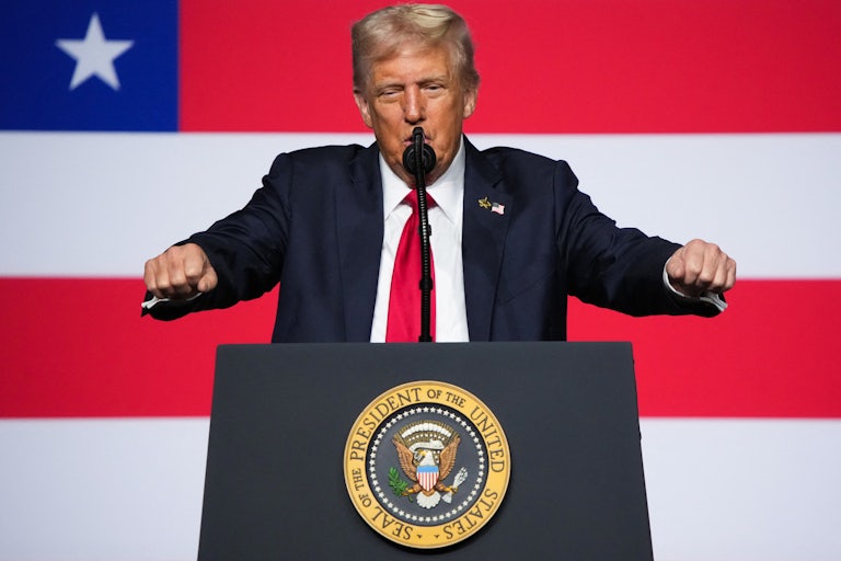 Donald Trump raises both arms with clenched fists.