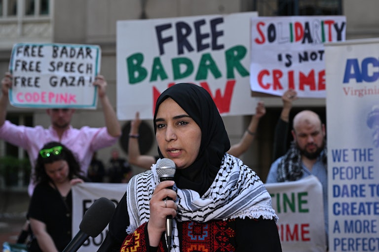 Badar Khan Suri's wife Mapheze Saleh speaks into a microphone while standing in front of signs calling for his release outside a courthouse in Alexandria, Virginia