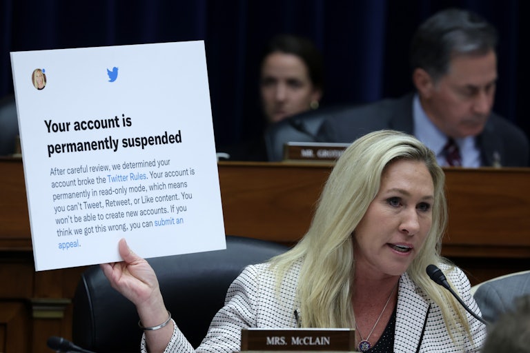 Representative Marjorie Taylor Greene (R-GA) holds up a poster of a Twitter announcement of suspending her account during a congressional hearing.