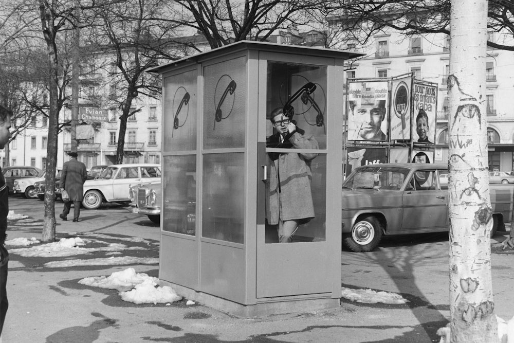 A man talking inside a telephone box