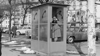 A man talking inside a telephone box