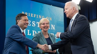 Joe Biden shakes hands with Ron Klain, standing in front of Jennifer Granholm.