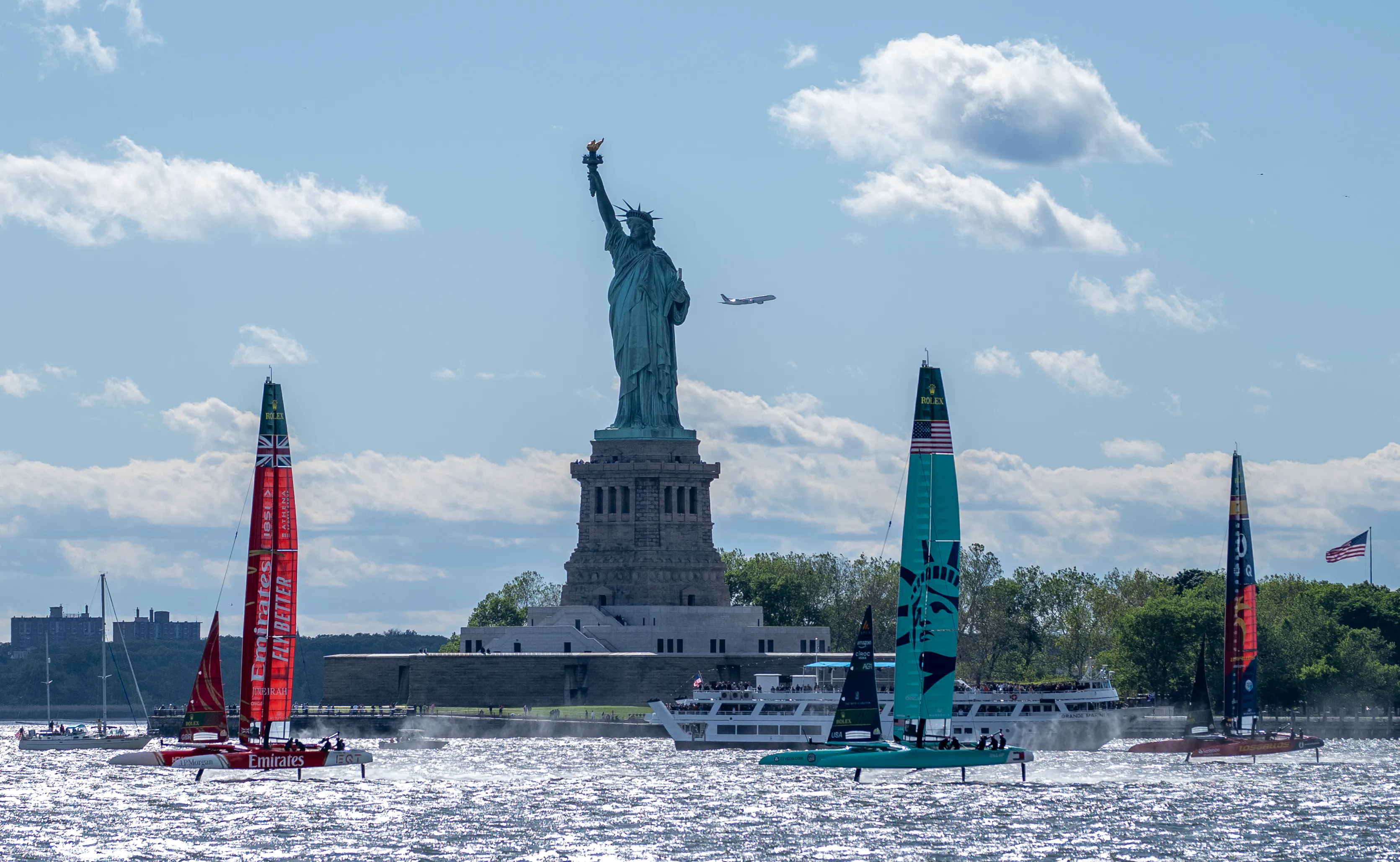 Boats sail in front of the Statue of Liberty