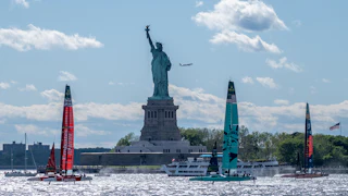 Boats sail in front of the Statue of Liberty