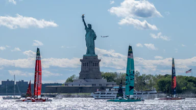 Boats sail in front of the Statue of Liberty