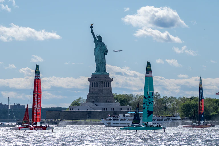Boats sail in front of the Statue of Liberty