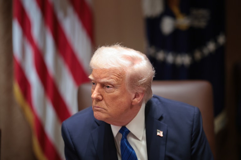 Donald Trump looks to the side while sitting in the White House