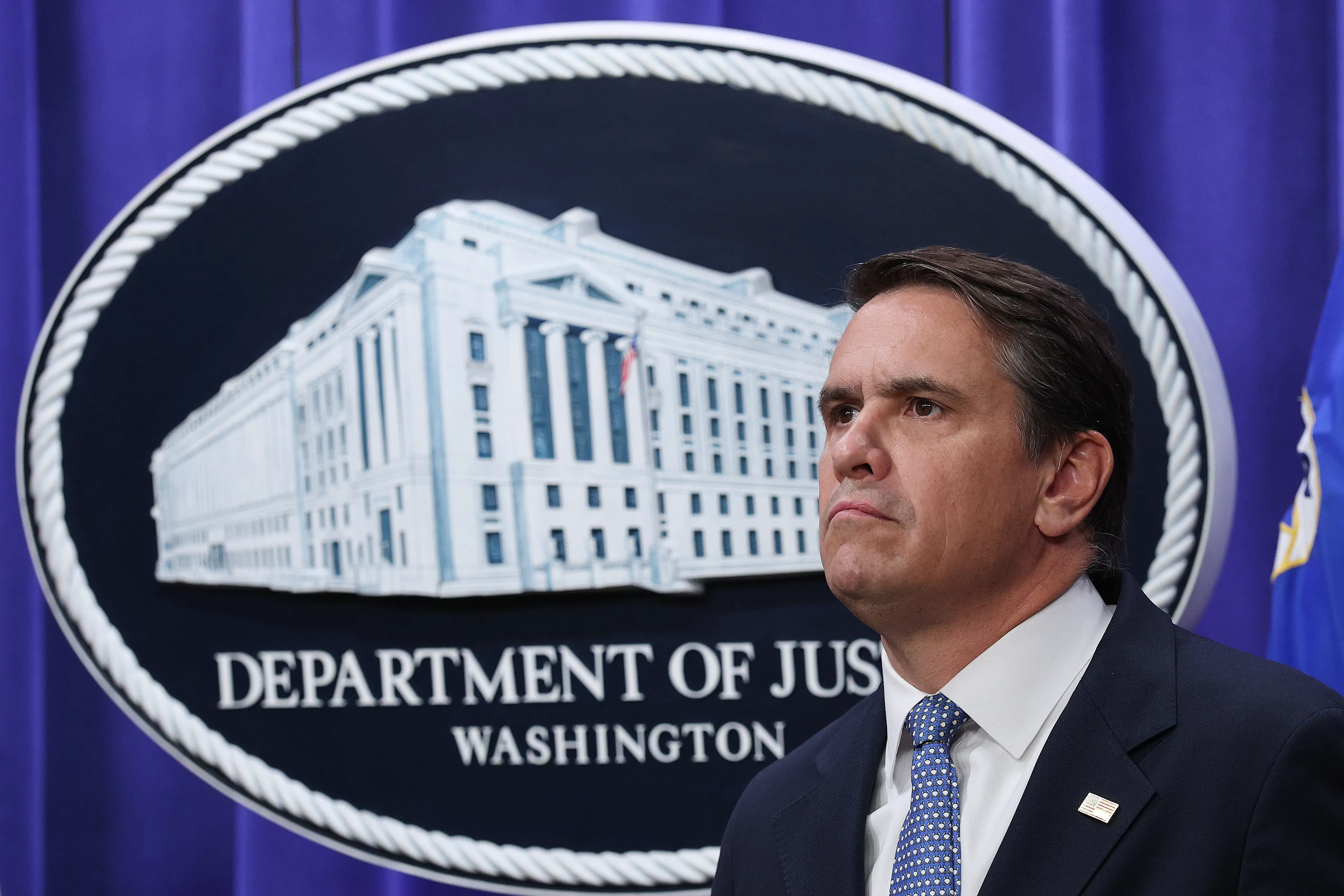 Acting Attorney General Todd Blanche stands in front of a Department of Justice logo