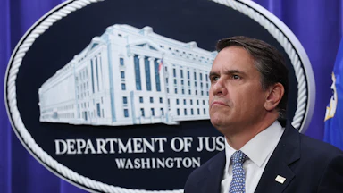 Acting Attorney General Todd Blanche stands in front of a Department of Justice logo