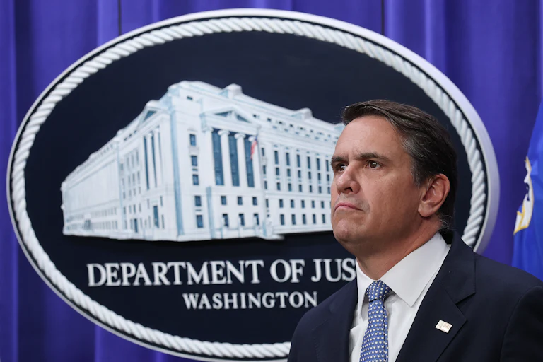 Acting Attorney General Todd Blanche stands in front of a Department of Justice logo