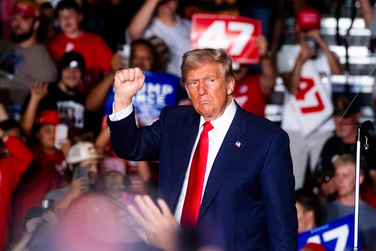 Donald Trump holds up his fist while onstage at a rally