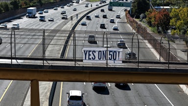 A Yes on 50 sign is posted on a walkway over the 101 in San Rafael, California.