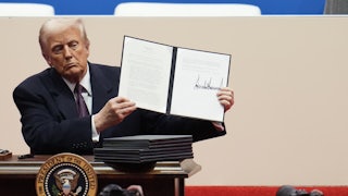 Donald Trump holds up a signed executive order during his inaugural parade