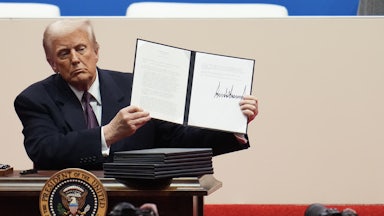 Donald Trump holds up a signed executive order during his inaugural parade