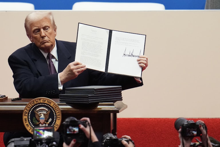 Donald Trump holds up a signed executive order during his inaugural parade