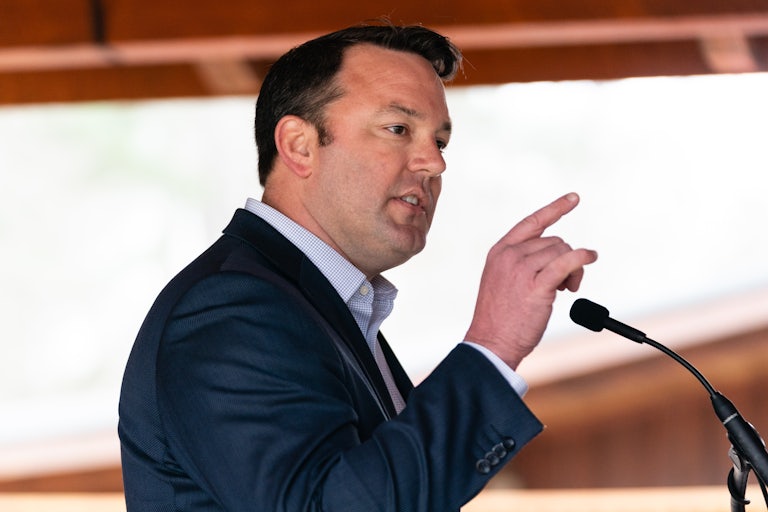 Burt Jones gestures with his finger while speaking into a microphone