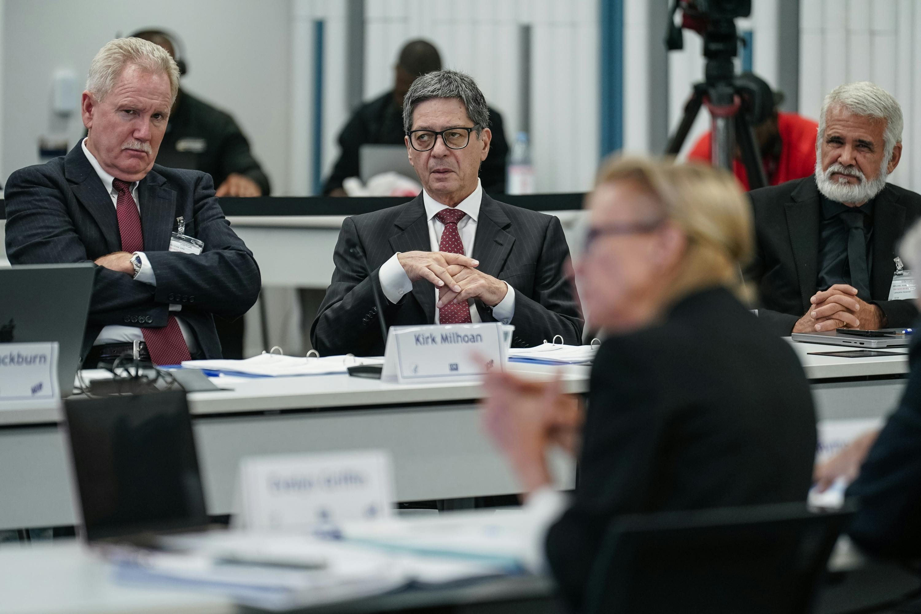 Kirk Milhoan, to left, crosses his arms and zones out while he sits at a table with others at a CDC meeting.
