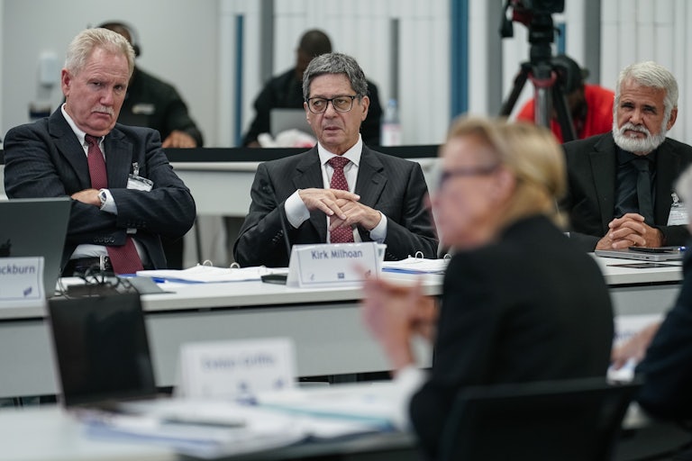 Kirk Milhoan, to left, crosses his arms and zones out while he sits at a table with others at a CDC meeting.