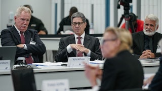 Kirk Milhoan, to left, crosses his arms and zones out while he sits at a table with others at a CDC meeting.