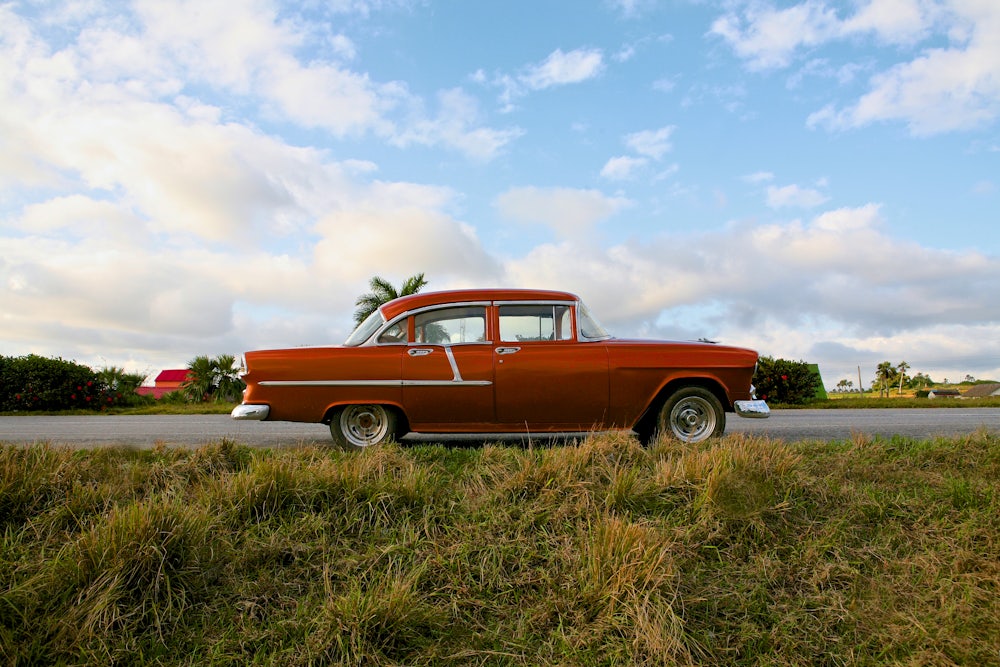 Photo of a 1950s era car parked along the roadside.