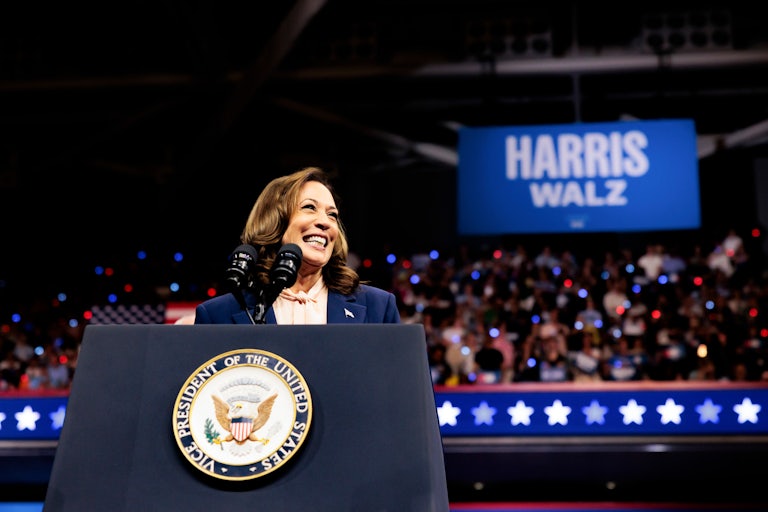 Kamala Harris smiles at the podium of her first campaign event with Tim Walz