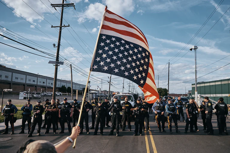 Someone waves an upside-down U.S. flag in front of a line of armed cops outside Delaney Hall.