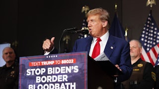 Donald Trump speaks at a podium with a sign on it that says "Stop Biden's Border Bloodbath"