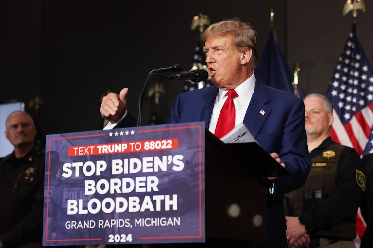 Donald Trump speaks at a podium with a sign on it that says "Stop Biden's Border Bloodbath"