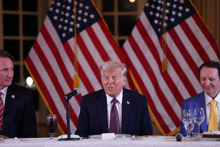 Donald Trump speaks while sitting at a table