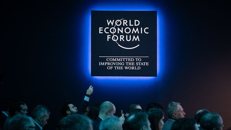 Attendees look toward the right under a World Economic Forum logo.