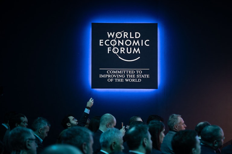 Attendees look toward the right under a World Economic Forum logo.