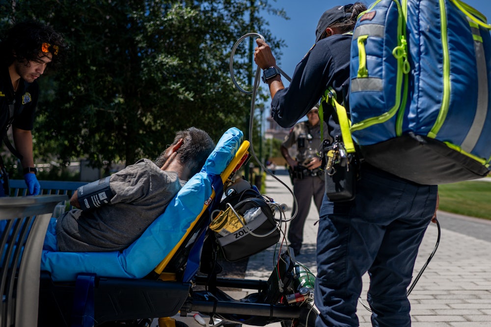 EMTs handle equipment as a person reclines on a stretcher outside.