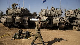 An Israeli soldier carries a tank shell after returning from the Gaza Strip