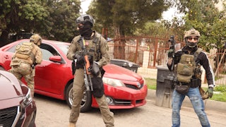 Masked federal immigration agents stand next to cars