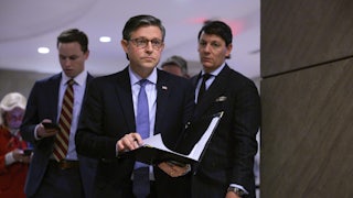 House Speaker Mike Johnson holds a folder with papers in his hands as he walks in the Capitol.