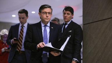 House Speaker Mike Johnson holds a folder with papers in his hands as he walks in the Capitol.