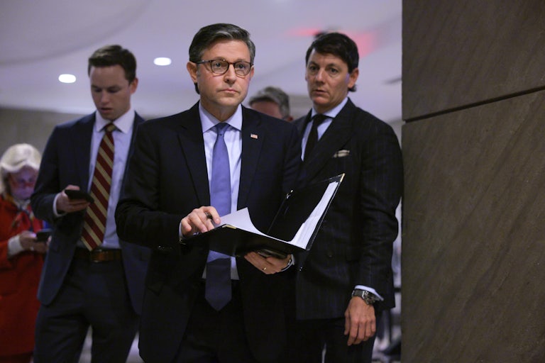 House Speaker Mike Johnson holds a folder with papers in his hands as he walks in the Capitol.