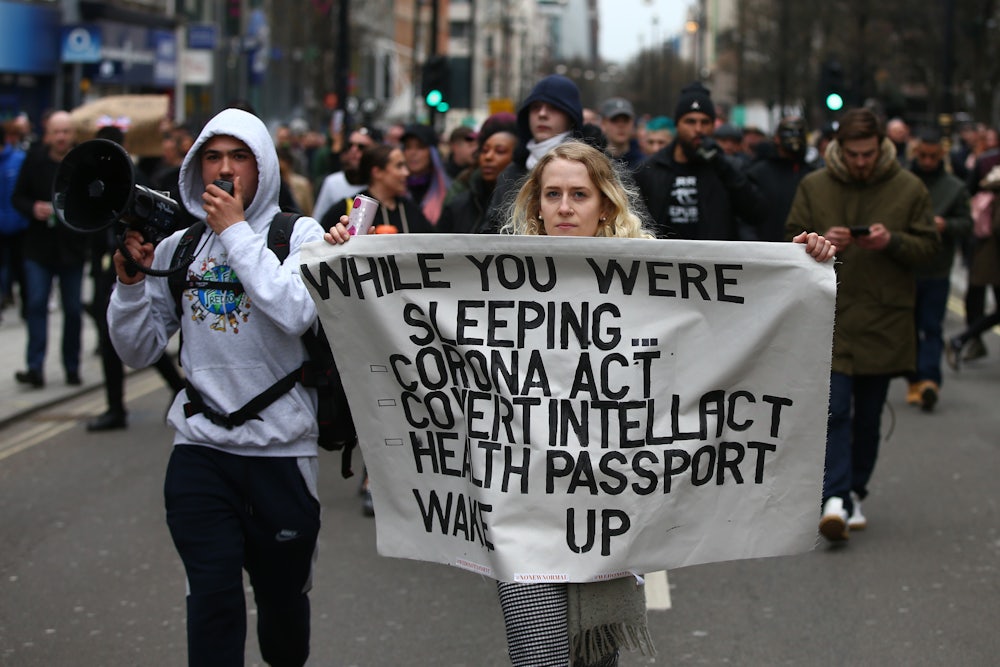 Protesters march with a poster during a protest linked to the QAnon conspiracy-theory