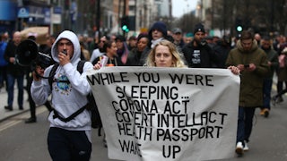 Protesters march with a poster during a protest linked to the QAnon conspiracy-theory