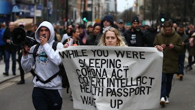 Protesters march with a poster during a protest linked to the QAnon conspiracy-theory