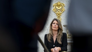 Lindsey Halligan purses her lips while leaning on the back of a chair in the Oval Office
