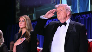 President Donald Trump salutes and First Lady Melania Trump puts a hand on her heart.