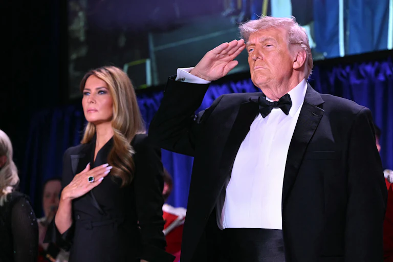 President Donald Trump salutes and First Lady Melania Trump puts a hand on her heart.