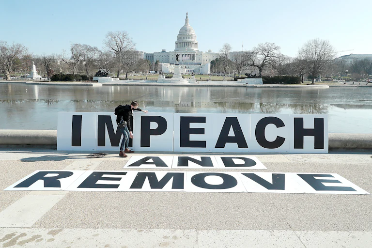 A man adjusts poster boards reading “IMPEACH AND REMOVE” on January 12, 2021, in Washington, D.C.