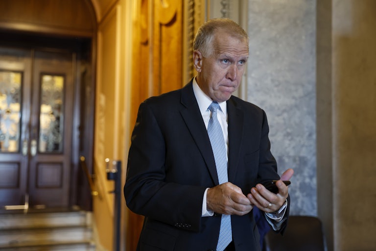 Republican Senator Thom Tillis walks through the Capitol with his phone in his hand.